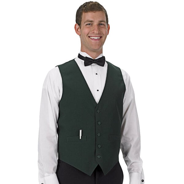 A man wearing a Henry Segal hunter green server vest and bow tie is smiling in a cocktail bar.
