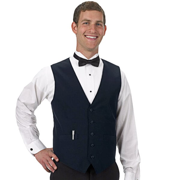 A man wearing a navy blue Henry Segal server vest with a bow tie.