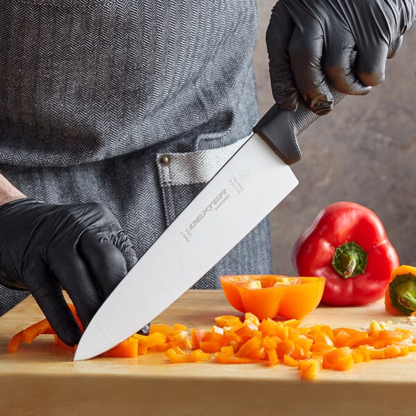 A person in black gloves using a Dexter-Russell SofGrip Chef Knife to cut an orange bell pepper.