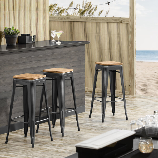 Lancaster Table & Seating Alloy Series Distressed Black Metal Indoor Industrial Cafe Bar Height Stool with Natural Wood Seat