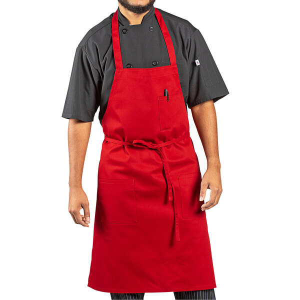 A man wearing a red Uncommon Chef bib apron with black pants.