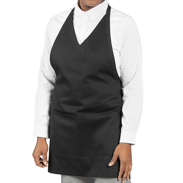 A woman wearing a black poly-cotton twill tuxedo apron with white trim.