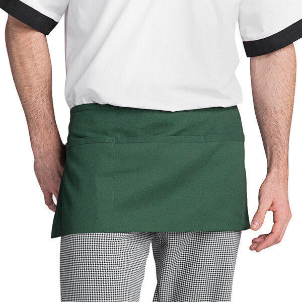A man wearing a Uncommon Chef hunter green waist apron with pockets.