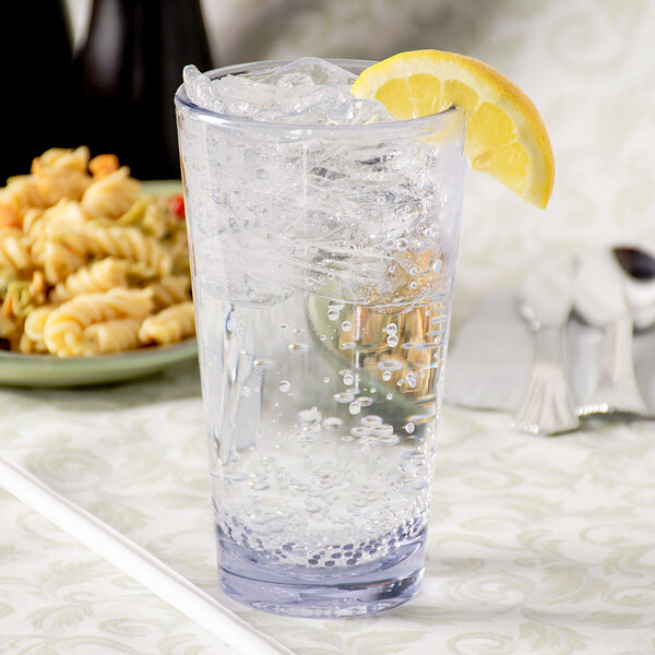 A Carlisle Alibi plastic glass of water with ice and a lemon wedge.
