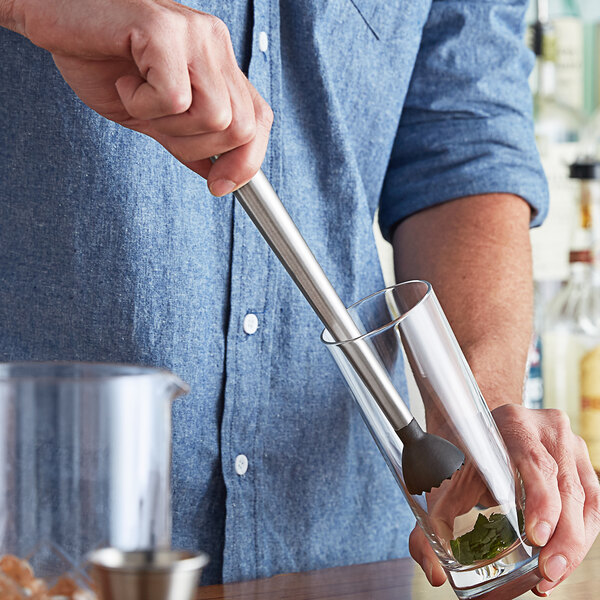 A person using an American Metalcraft stainless steel muddler in a glass.