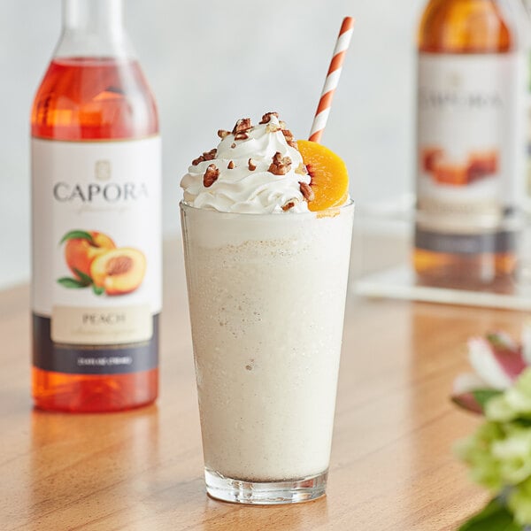 A glass of milkshake made with Capora Peach Flavoring Syrup topped with peaches.