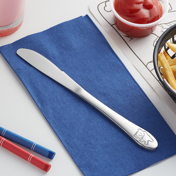 An Acopa stainless steel medium weight knife on a blue napkin next to a bowl of french fries and ketchup.