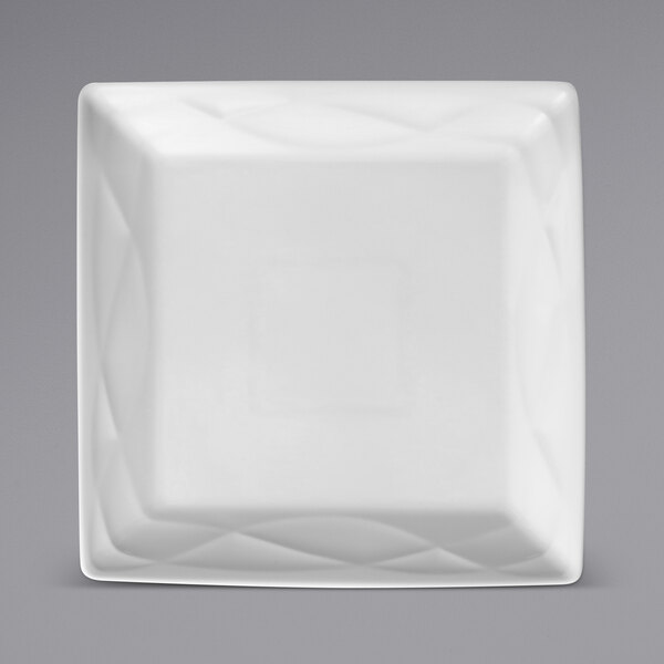 A close up of a Sant'Andrea Pensato white square porcelain plate with a design on the rim.