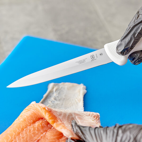A person in gloves using a Mercer Culinary Ultimate White Fillet Knife to cut a piece of meat.