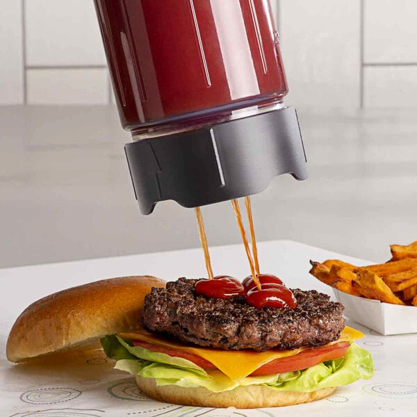 A close up of a hamburger with ketchup served with fries using a Server ProPortion Triple-Tip Dispenser.