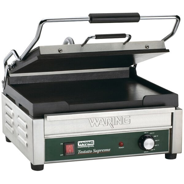 A Waring Tostato Supremo panini grill with a green and black handle.