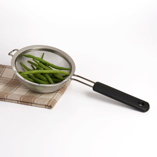 An OXO stainless steel strainer with green beans in it.