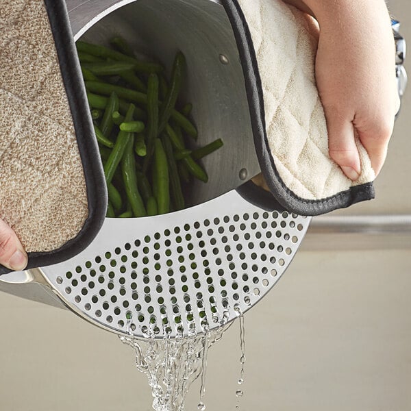 A person using a Fox Run stainless steel pot strainer to wash green beans in a pot.