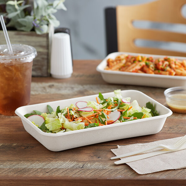 A salad in a white Eco-Products rectangle take-out container on a table.