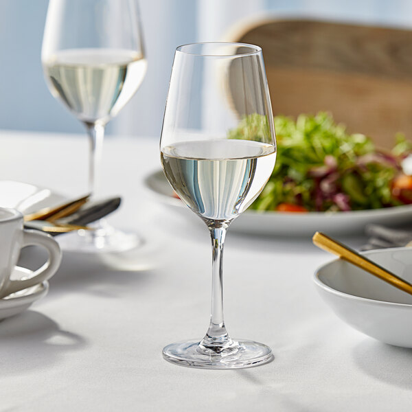 A Lucaris Temptation Riesling wine glass filled with white wine on a table.