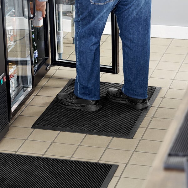 A man standing on a Choice black rubber anti-fatigue mat.