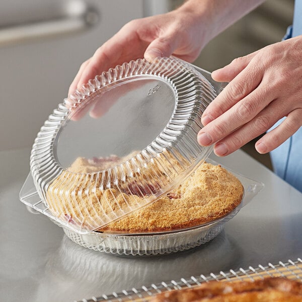 A person holding a Choice clear plastic container with a pie inside.