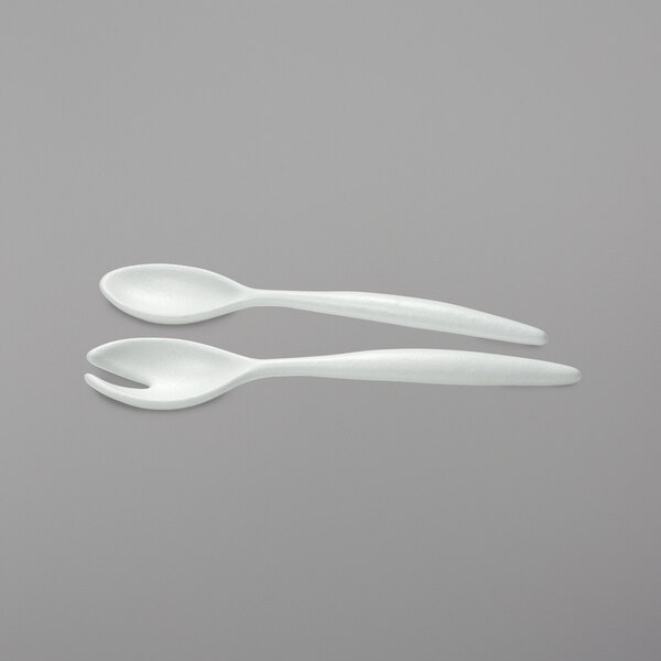 White plastic salad servers. Two white spoons and forks.