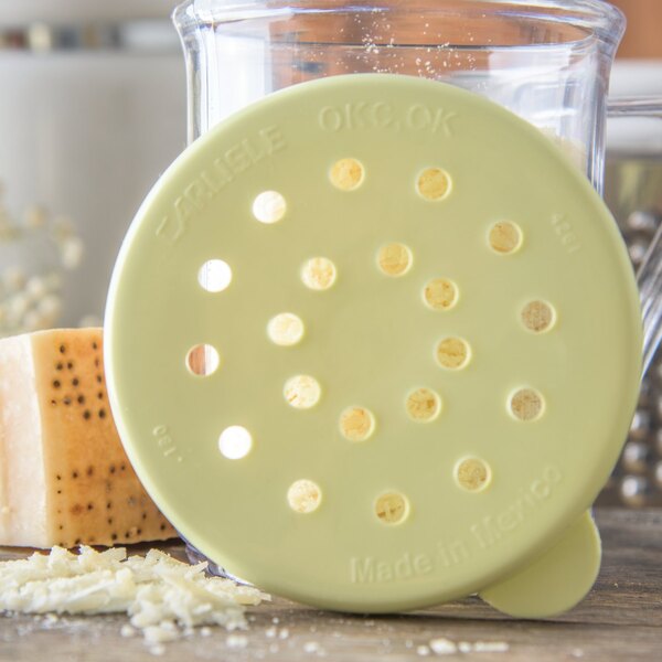 A yellow circular lid with holes on a white table.