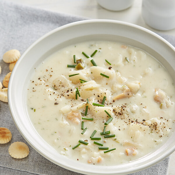 A bowl of Knorr clam chowder soup with crackers and a spoon.