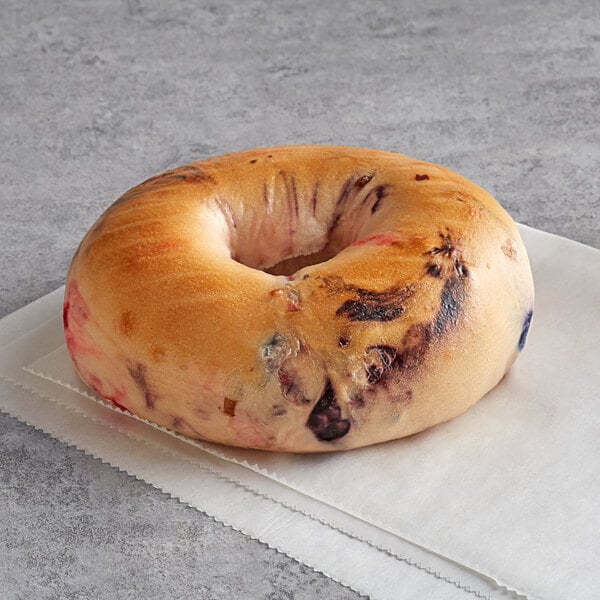 A New York Style Very Berry bagel with a hole in the middle on a napkin.