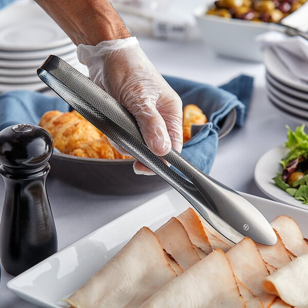 A person holding American Metalcraft hammered black vintage tongs over food.