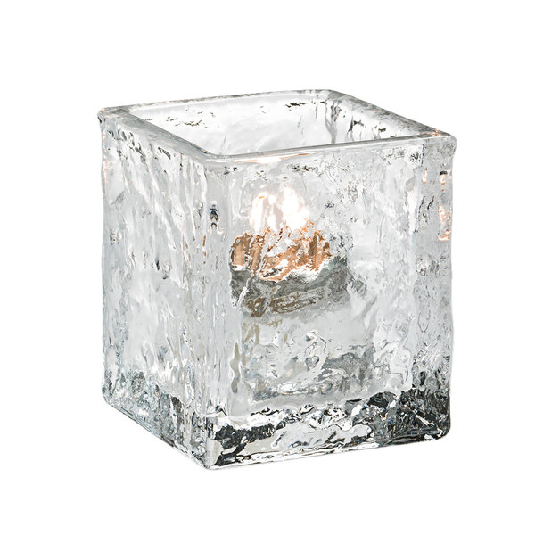 A Hollowick Glacier clear glass tealight candle holder with a lit candle inside.