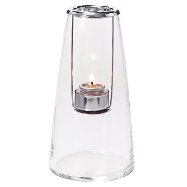 A Hollowick clear glass tealight lamp with a lit candle inside.
