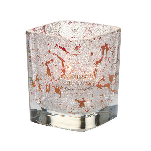 A Hollowick glass square votive candle holder with red splatters.