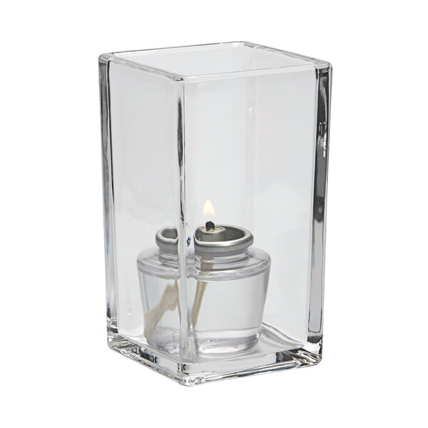 A clear glass Hollowick Quad votive with a lit candle inside.