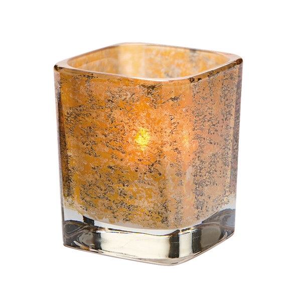A Hollowick glass square votive with a lit candle inside.