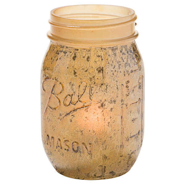 An Antique Gold glass jar with a Hollowick candle inside.