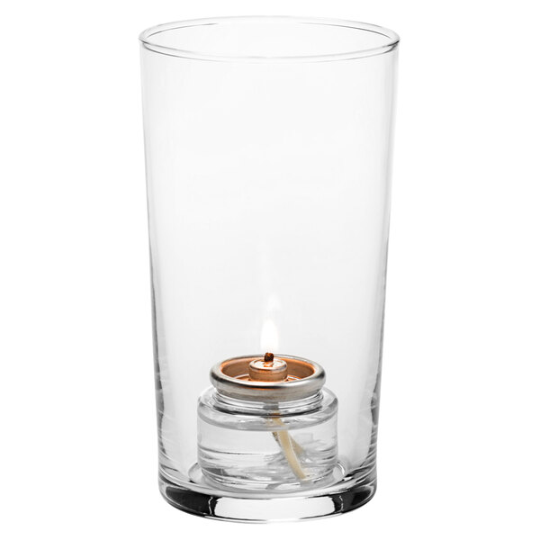 A Hollowick clear glass candle holder with a lit candle inside.