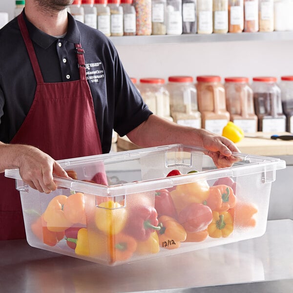 A man holding a Vigor clear polycarbonate food storage container full of peppers.