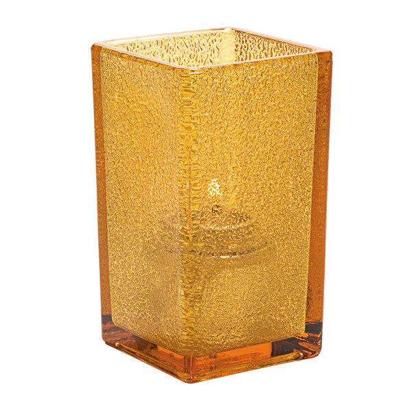 A Hollowick Quad Amber Jewel glass candle holder with a candle inside.