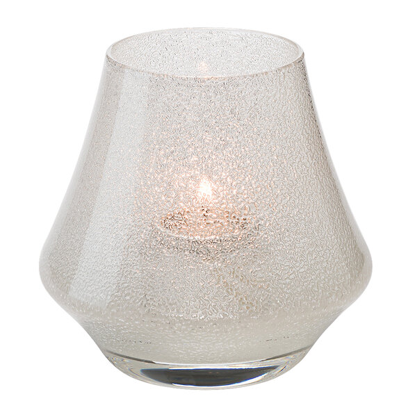 A Hollowick clear glass candle holder with a lit candle.