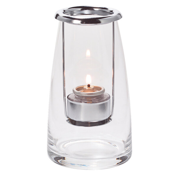 A Hollowick clear glass lighthouse tealight lamp with a lit candle inside.