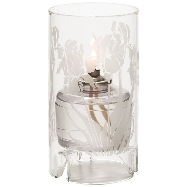A Hollowick Iris etch glass candle holder with a lit white candle inside.