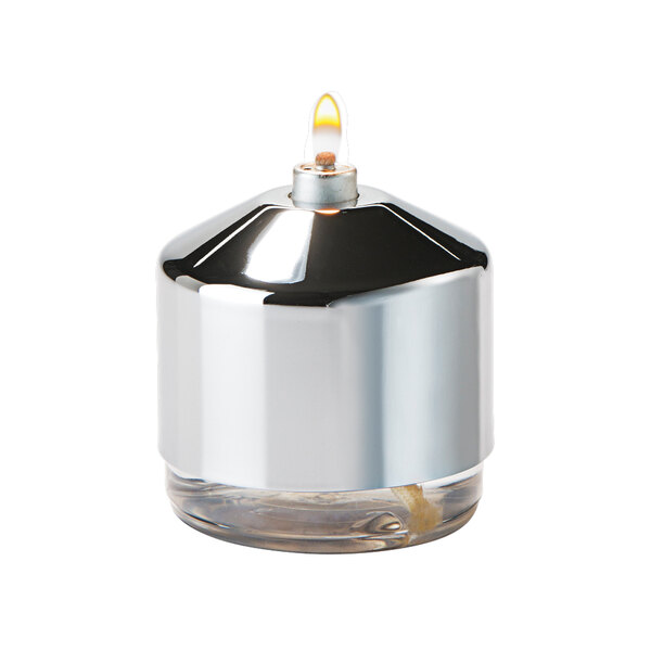 A silver Hollowick candle cover over a glass candle holder with a yellow flame.