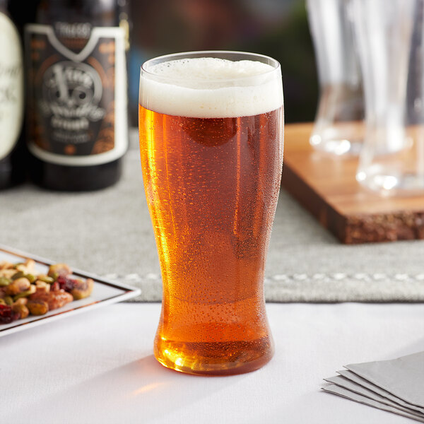 A Choice clear plastic pilsner glass filled with beer on a table.