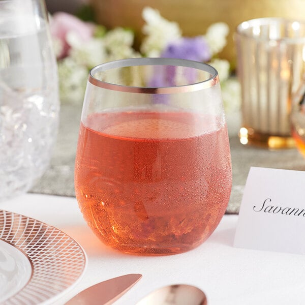 A Visions stemless wine glass with a copper rim full of red liquid on a table.