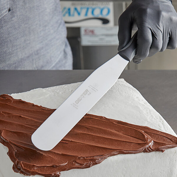 A hand using a Dexter-Russell V-Lo baking spatula to ice a cake.