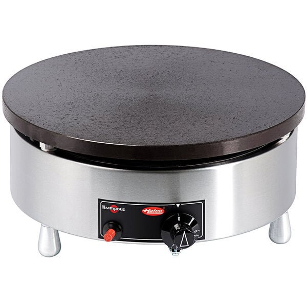 A Hatco Krampouz round metal crepe maker with a black surface and handle.