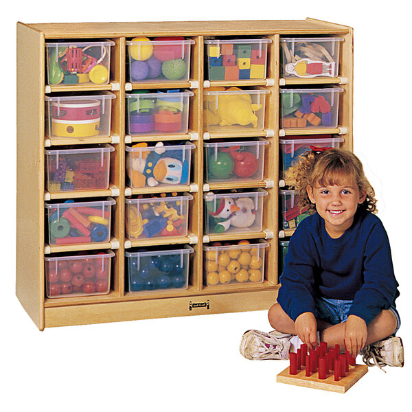 A young girl sitting next to a Jonti-Craft wood toy storage cabinet with plastic bins inside.