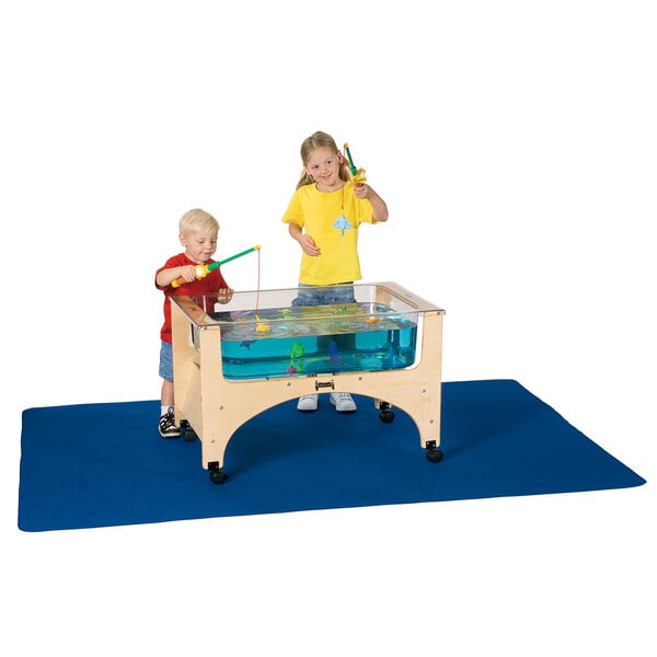 A boy and girl play with toys on a blue Jonti-Craft sensory table mat.