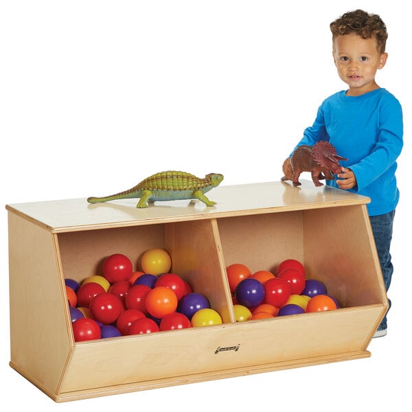 A child standing next to a Jonti-Craft wood toy crate filled with toys.