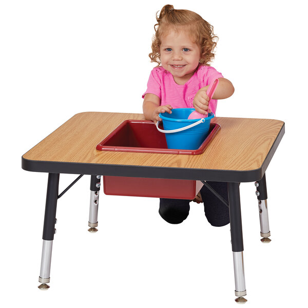 A little girl playing with a bucket on a Jonti-Craft sensory table.