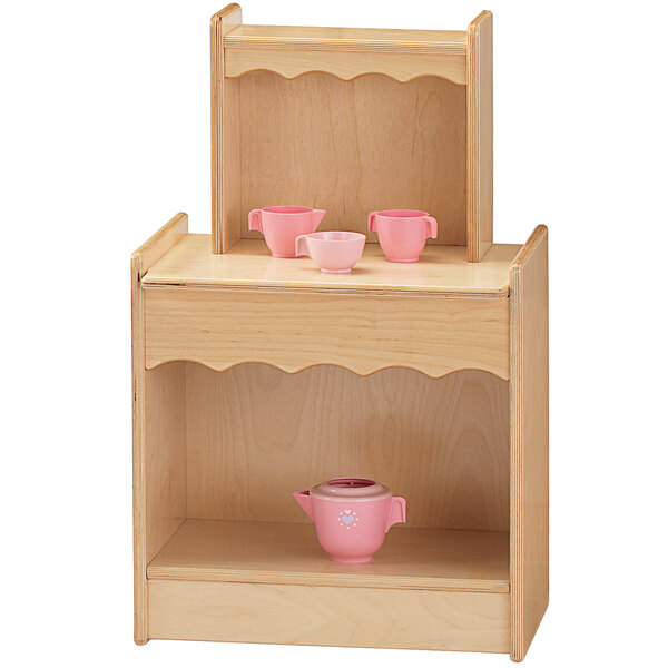 A Jonti-Craft wooden toy kitchen cupboard with pink cups and a teapot.