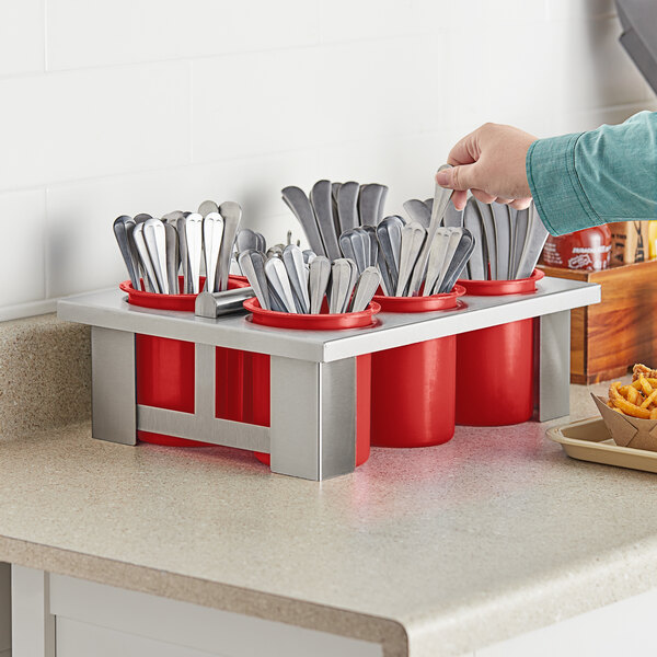A person putting utensils in a red Steril-Sil flatware container.