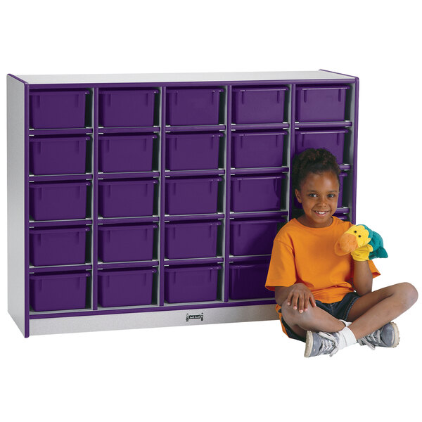 A young girl sitting next to a Rainbow Accents purple storage cabinet with purple trays.